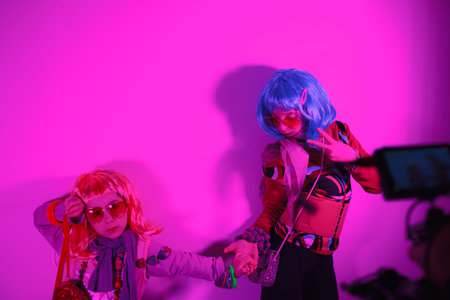 Little girls wearing a colorful wig and heart-shaped sunglasses posed for a photo shooting on the...