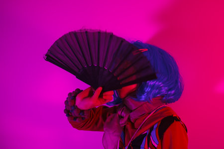 Little girl posing with a fan for a photo shoot on a fuchsia background
