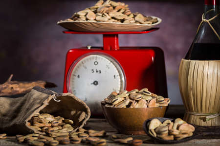 Composition with dried broad beans, whine and weight scale in a wooden tableの写真素材