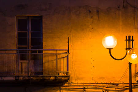 View of old balcony at night illuminated from street lampの写真素材