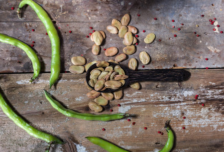 Top view of fresh and dried broad beans in the wooden table