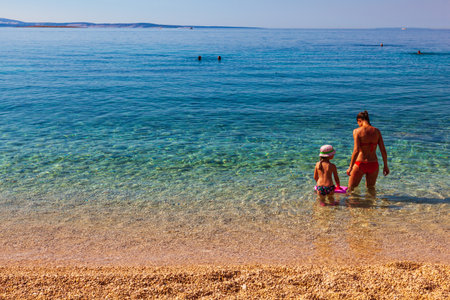 Stara Baska, Croatia - July, 21: Mother and daughter playing in the shoreline of the beautiful Oprna beach on July 21, 2020のeditorial素材