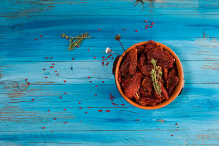 Top view of Mediterranean dried tomatoes inside a bowl on blue rustic woodenの写真素材