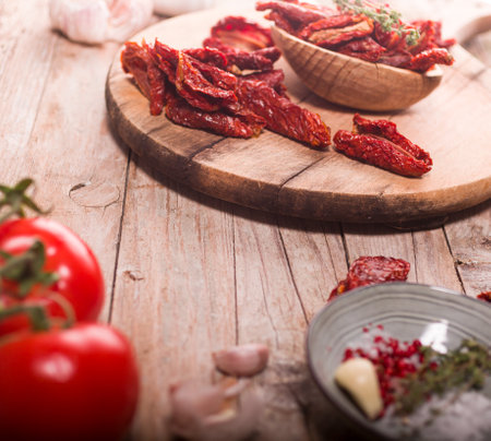 Mediterranean dried tomatoes garlic, thyme and fresh tomatoes on wooden tableの写真素材
