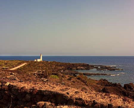View of lighthouse in the scenic lava rock cliff, Linosa island. Sicilyの写真素材