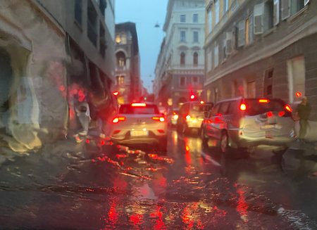 Rain on street with color lighting at a traffic evening, view from the car on the road when it...
