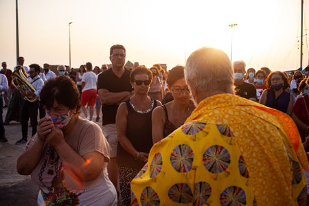 Linosa, Italy - July 25: Priest give host at faithful in the Procession of the Stella Maris during the religious patronal feast of the Madonna of the sea on July 25, 2021のeditorial素材