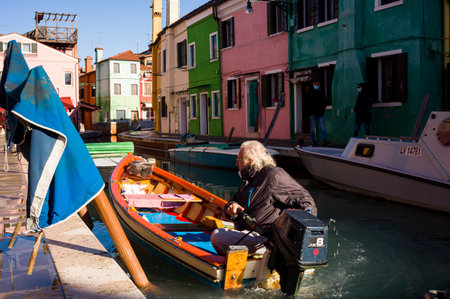 Burano, Italy - January, 06: Italian elderly on his boat navigating in the Burano canal on January 06, 2022のeditorial素材