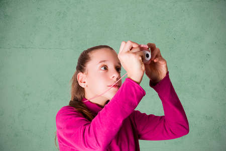Little Girl Taking Picture Using Toy Photo Camera on green backgroundの写真素材