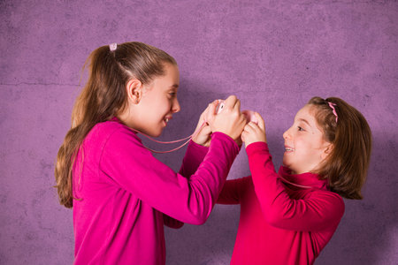 Couple of Little Girls Taking Picture Using Toy Photo Camera on pink background