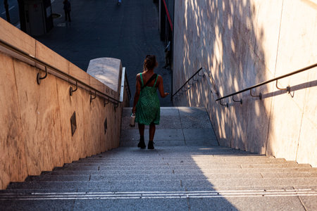 Rear view of young woman coming down stairs in Paris. City tourism concept