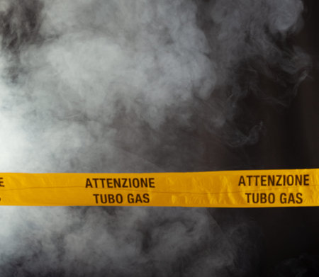 Yellow emergency sign of attention gas pipe on smoke-filled background. On the yellow tape the...