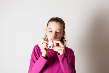 Little Girl Taking Picture Using Toy Photo Camera on white backgroundの写真素材