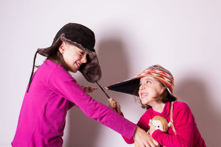 The little sisters who wear winter hats and red pullovers quarrel and fight and compete for a teddy...