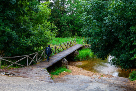 Pilgrim walking on the wooden bridge over the river along the Camino de Santiago or Way of St. James