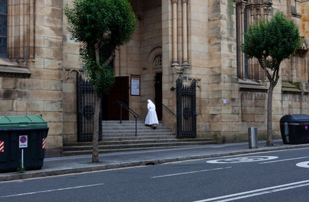 Bilbao, Spain - August 03, 2022: A nun wearing a white habit is climbing the stairs of the church of...