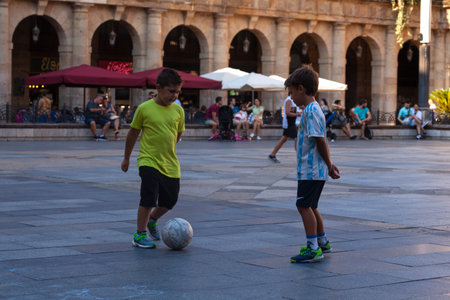 Bilbao, Spain - August 02, 2022: Two glad children playing football on the streetのeditorial素材