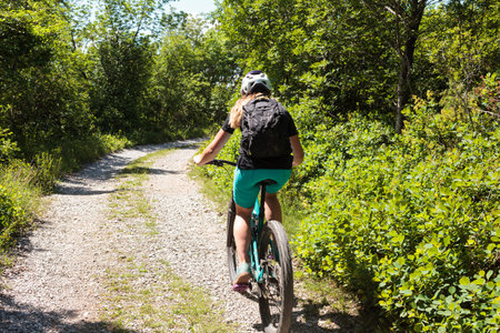 Mountain biking young woman riding on bike in summer mountains forest landscape in Slovenia
