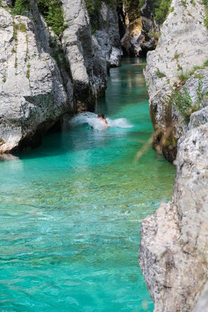 Lepena, Slovenia - July 17, 2024: Man diving into the Soca Gorge, Soca riverの写真素材