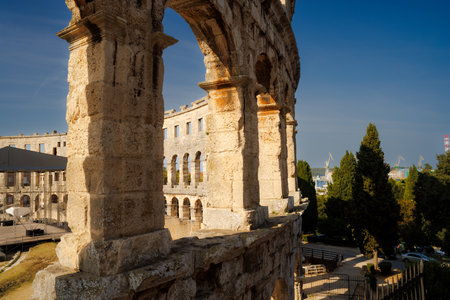 Ancient heritage in Pula, Istria, Croatia. Arches of monumental ancient Roman arena. Detail of historic amphitheater, wide angle view of high walls on blue sky background.の写真素材