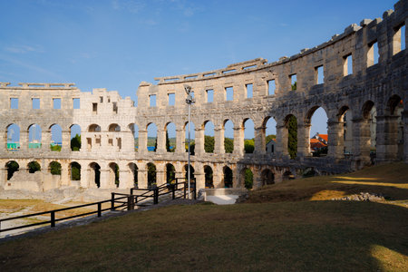 Ancient heritage in Pula, Istria, Croatia. Arches of monumental ancient Roman arena. Detail of historic amphitheater, wide angle view of high walls on blue sky background.の写真素材