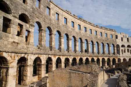 Ancient heritage in Pula, Istria, Croatia. Arches of monumental ancient Roman arena. Detail of historic amphitheater, wide angle view of high walls on blue sky background.の写真素材