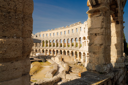 Ancient heritage in Pula, Istria, Croatia. Arches of monumental ancient Roman arena. Detail of historic amphitheater, wide angle view of high walls on blue sky background.の写真素材