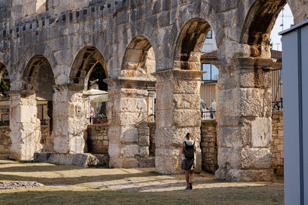Woman walking on historic Roman arena in Pula, Croatia. Travel concept. Young woman enjoys summer Croatian vacation in Europeの写真素材