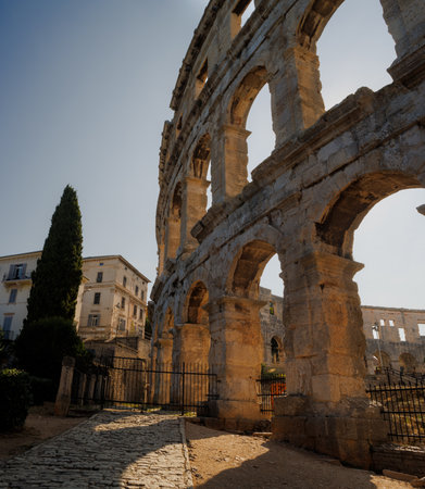 Ancient heritage in Pula, Istria, Croatia. Arches of monumental ancient Roman arena. Detail of historic amphitheater, wide angle view of high walls on blue sky background.の写真素材