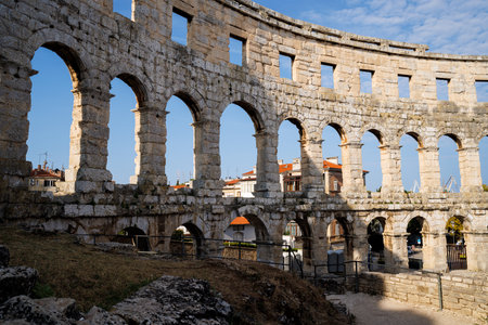 Ancient heritage in Pula, Istria, Croatia. Arches of monumental ancient Roman arena. Detail of historic amphitheater, wide angle view of high walls on blue sky background.の写真素材