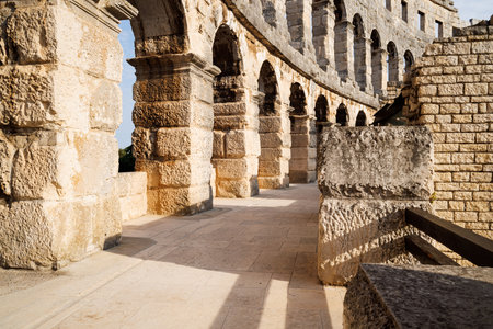 Ancient heritage in Pula, Istria, Croatia. Arches of monumental ancient Roman arena. Detail of historic amphitheater, wide angle view of high walls on blue sky background.の写真素材