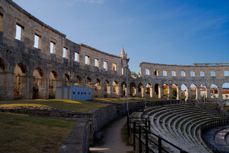 Ancient heritage in Pula, Istria, Croatia. Arches of monumental ancient Roman arena. Detail of historic amphitheater, wide angle view of high walls on blue sky background.の写真素材