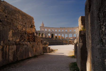 Ancient heritage in Pula, Istria, Croatia. Arches of monumental ancient Roman arena. Detail of historic amphitheater, wide angle view of high walls on blue sky background.の写真素材
