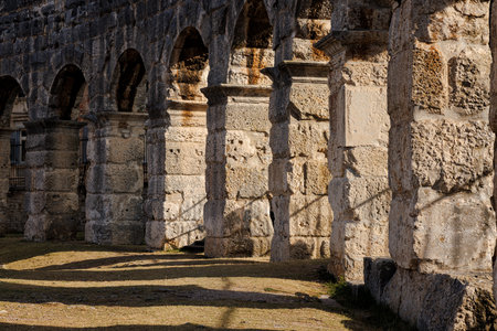 Ancient heritage in Pula, Istria, Croatia. Arches of monumental ancient Roman arena. Detail of historic amphitheater, wide angle view of high walls on blue sky background.の写真素材