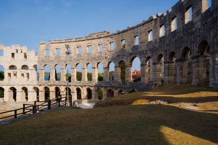 Ancient heritage in Pula, Istria, Croatia. Arches of monumental ancient Roman arena. Detail of historic amphitheater, wide angle view of high walls on blue sky background.の写真素材