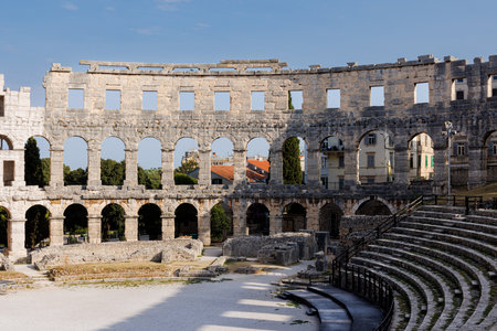 Ancient heritage in Pula, Istria, Croatia. Arches of monumental ancient Roman arena. Detail of historic amphitheater, wide angle view of high walls on blue sky background.の写真素材