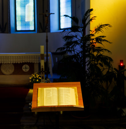 Open Bible placed on the church lectern, highlighted in the quiet interior of an old wooden-pew sanctuary. Soft light, spiritual atmosphere, simple Christian setting in the Church of the Good Shepherd, Trieste.の写真素材