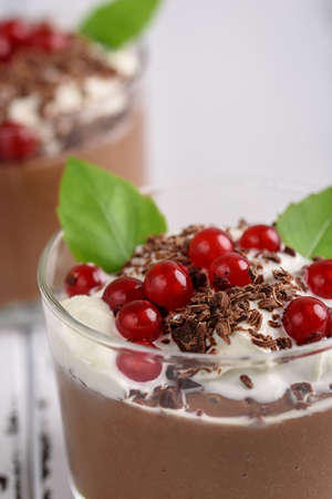 Chocolate mousse with currant and mint in a glasses on a whiite wooden backgroundの写真素材