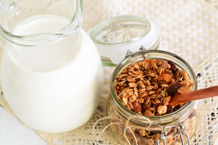 Homemade granola with nuts, cranberries and dried apricots, and a jug of milk. selective focus, copy spaceの写真素材