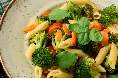 Italian home cooking. Vegetable pasta with broccoli, cherry tomatoes, carrots, garlic and basil. Top viewの写真素材