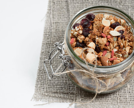 Homemade granola in a glass jar on white background