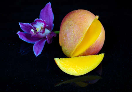Close-up studio shot mango fruit with slice and leaf isolated on black backgroundの写真素材