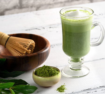 Matcha green tea latte beverage in glass cup on white background