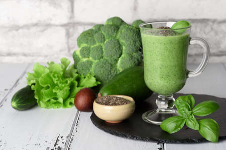 Blended green smoothie with ingredients on wooden tableの写真素材