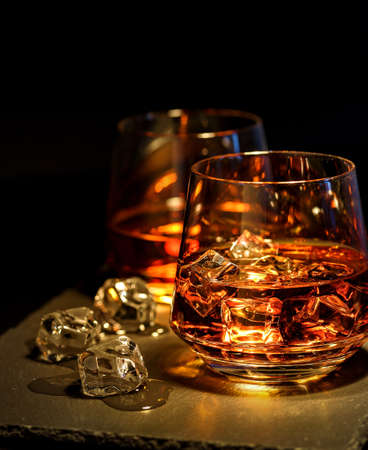 Two glasses of whiskey with ice on a black backgroundの写真素材