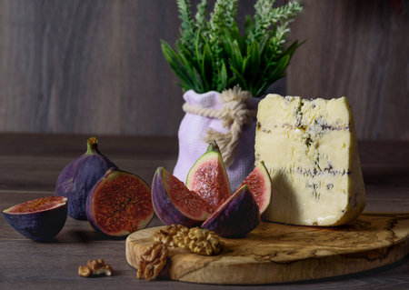 a glass of red wine with snacks of cheese, grapes of figs and nuts on wooden table