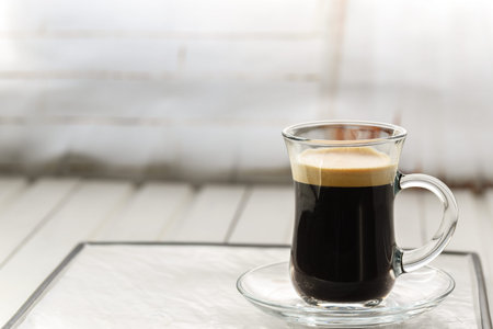 Espresso. Glass espresso cup with coffee beans on a light background