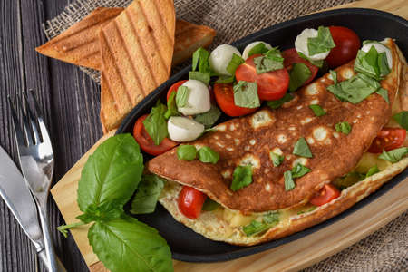 Vegetables omelette with tomatoes, basil, mozzarella, toast. Rusticの写真素材