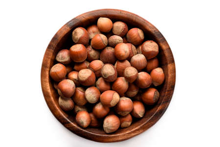 Hazelnuts in a wood bowl and loose isolated over white background.の写真素材