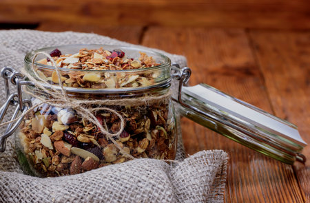 Healthy breakfast homemade granola in glass jar on wooden backgroundの写真素材